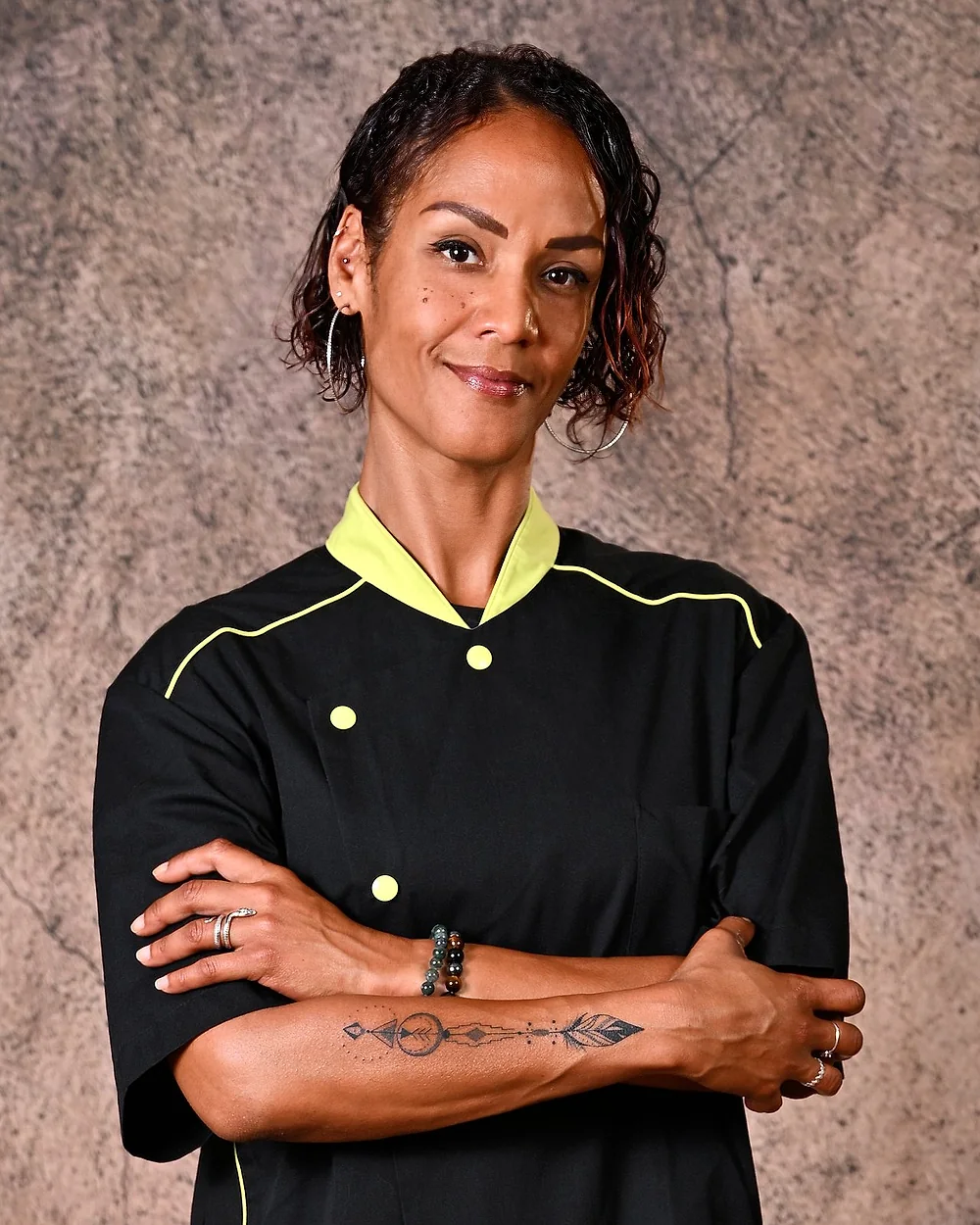 Nathalie, cheffe à domicile à Bordeaux, en veste de cuisine, bras croisés, sourire aux lèvres